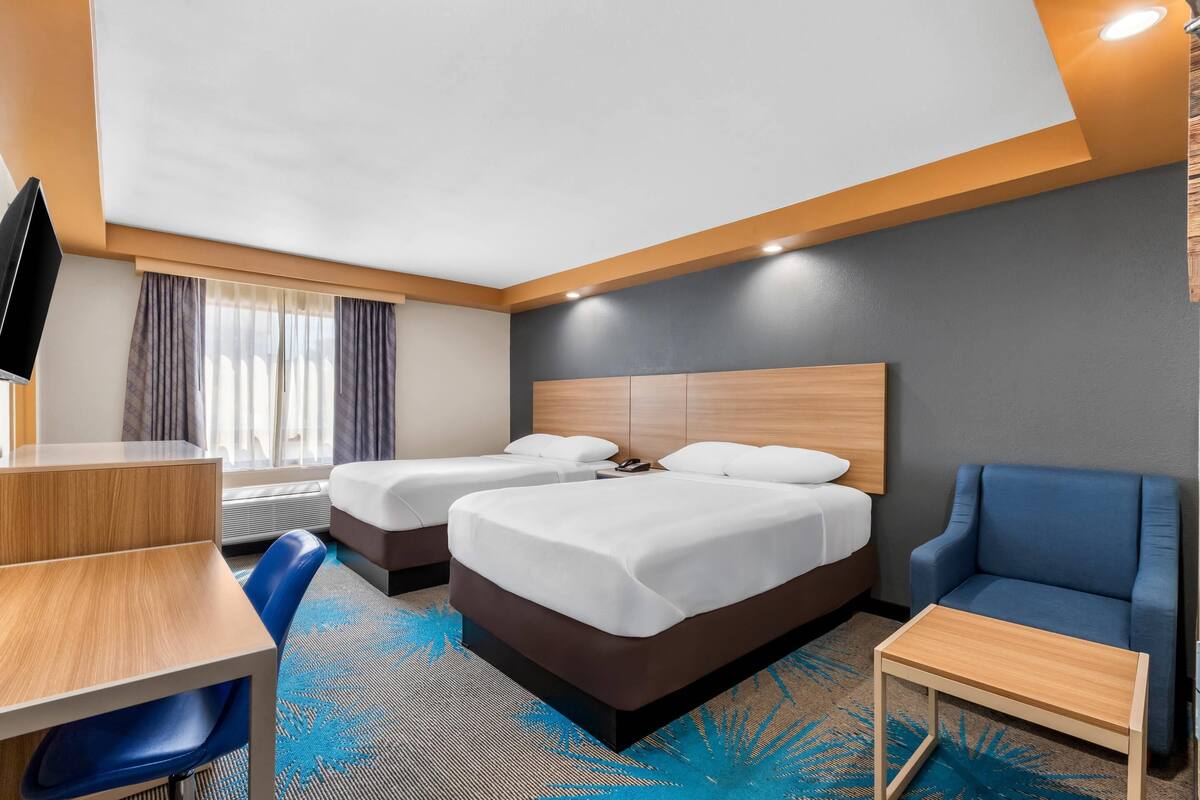 Ett hotellrum med två sängar, ett skrivbord, en stol och en TV.