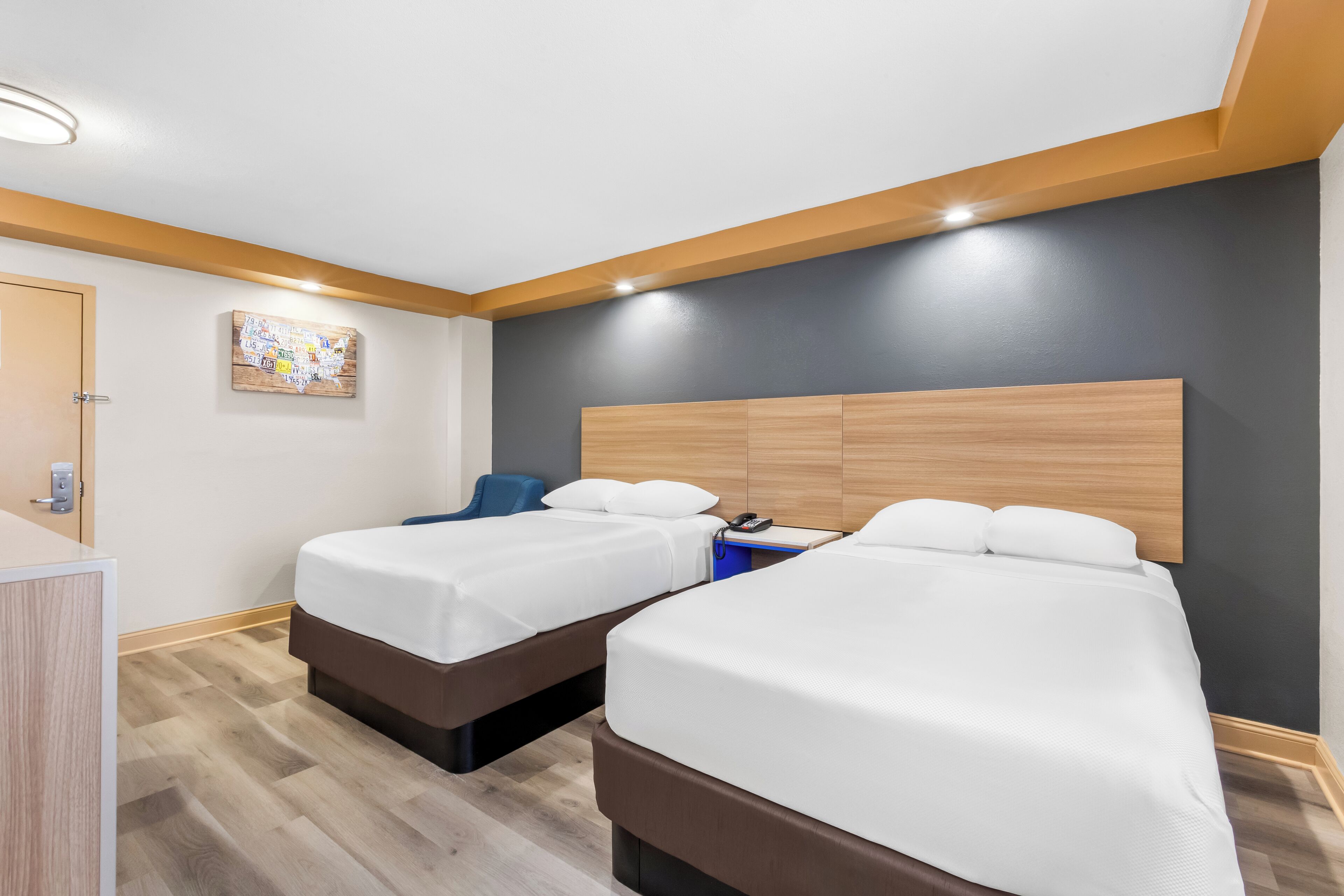 A hotel room with two beds, a wooden headboard, a desk, and a wall-mounted artwork.
