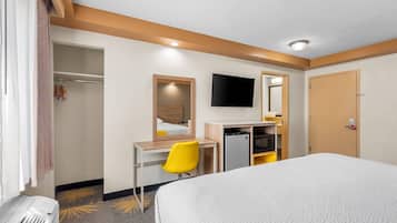 A hotel room with a bed, a desk with a chair, a TV, and a wardrobe.