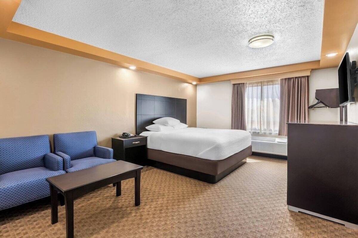 Ett hotellrum med en säng, en soffa, ett skrivbord och en tv.