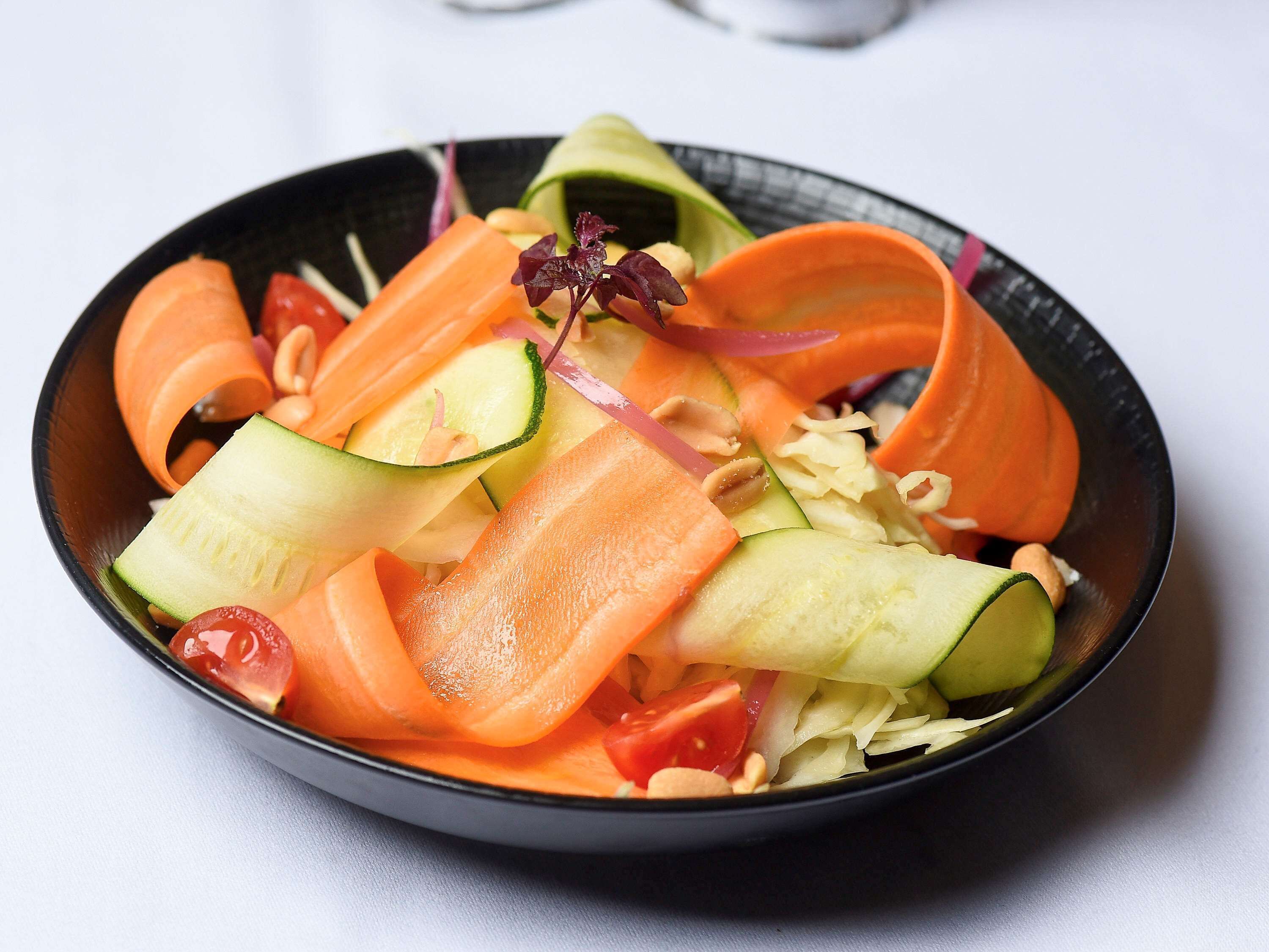 A bowl of salad with various vegetables and nuts.