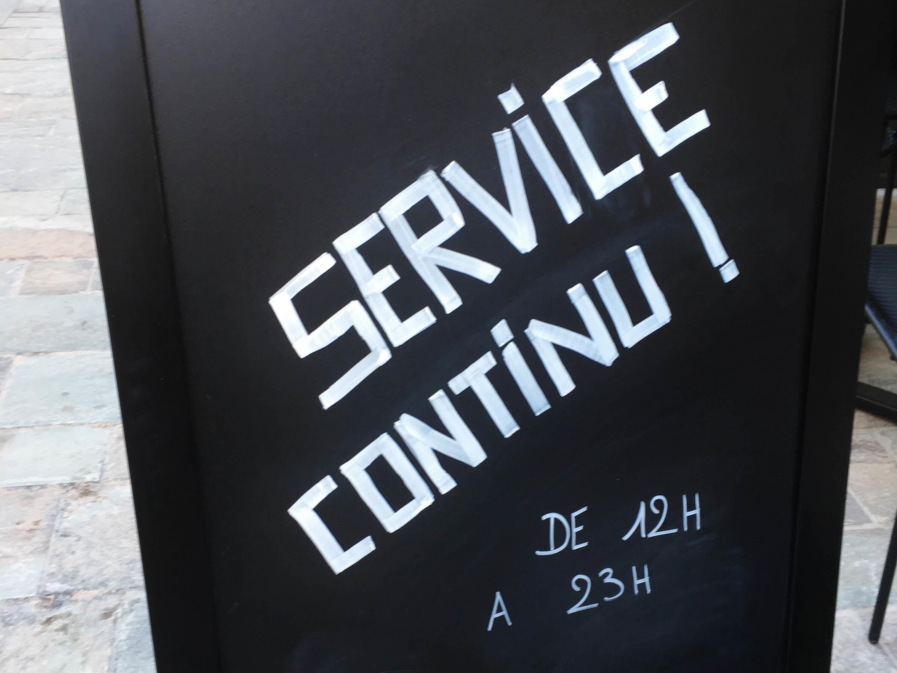 A sign with the text 'SERVICE CONTINUED' and 'DE 12H A 23H'.