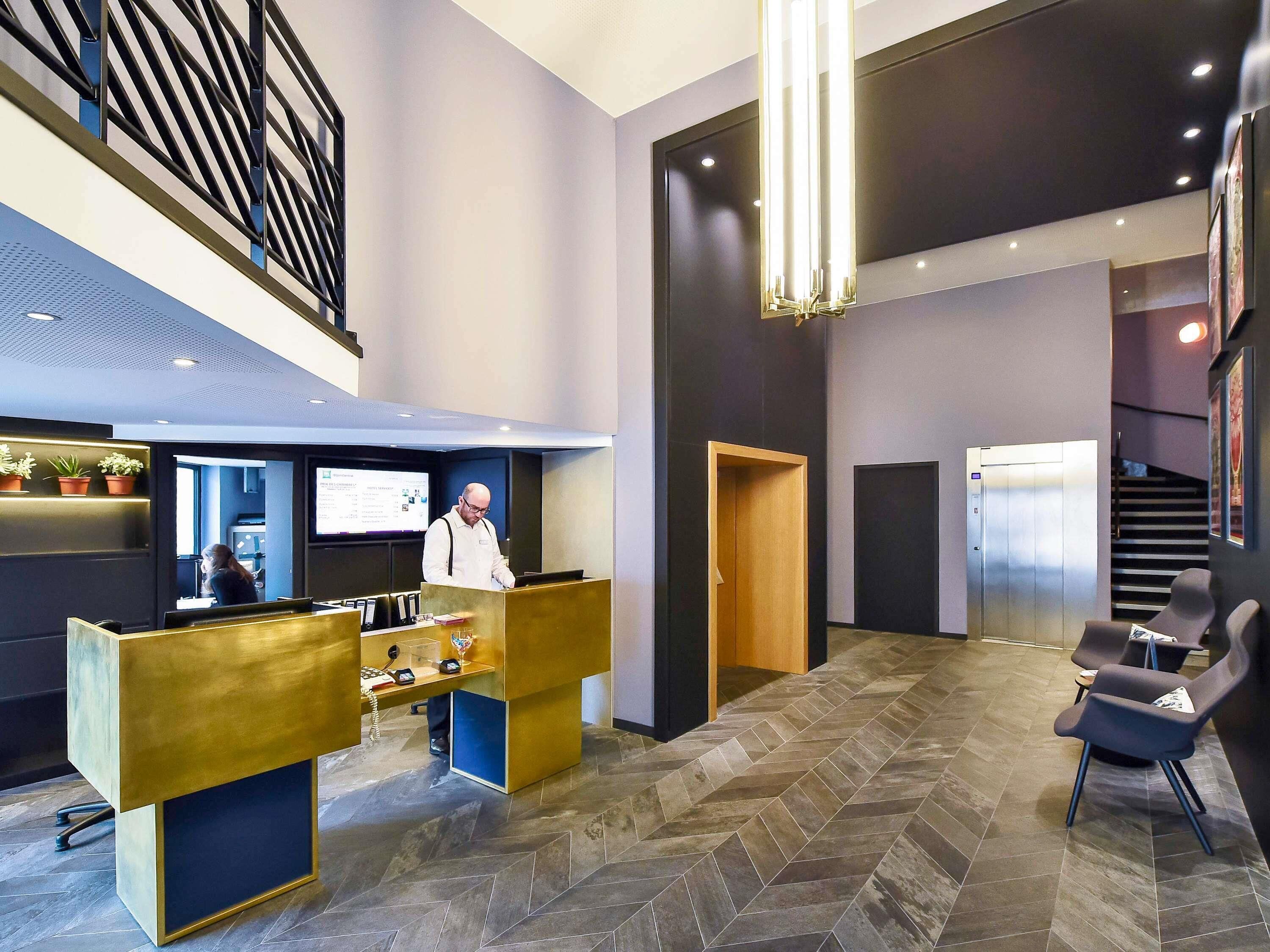 A reception area with a desk, chairs, a staircase, and an elevator.