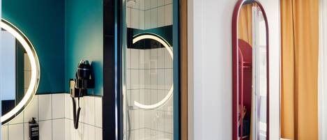 Un baño de hotel moderno con ducha, lavabo y espejo.