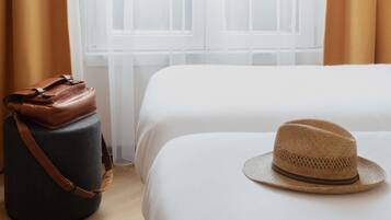 Une chambre d’hôtel avec un lit, une valise et un chapeau posé sur le lit.