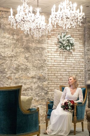 A room with a brick wall, a chandelier, and a blue armchair with a cushion. - St James Hotel, a Historic Hotel of America (Red Wing)