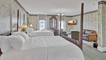 A hotel room with a large bed, two bedside tables, a desk, a chair, and a sofa.