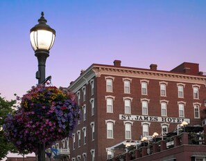 A historic brick building labeled "St. James Hotel" with a classic street lamp and hanging flower basket.