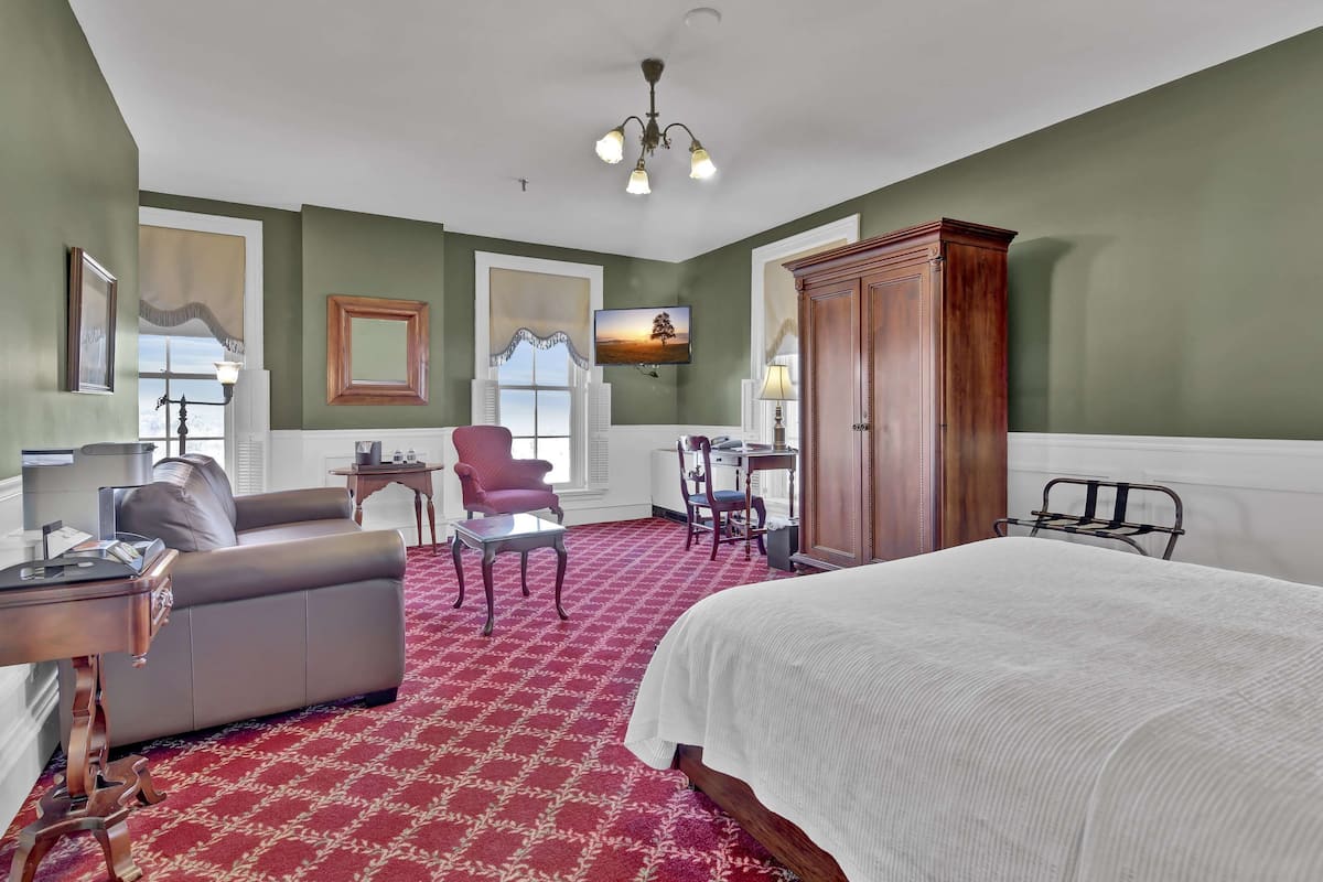 Een hotelkamer met een groot bed, een slaapbank, een bureau en een televisie.