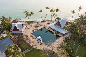 A resort with a swimming pool, lounge chairs, and palm trees.