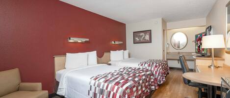 Een hotelkamer met twee bedden, een bureau, een stoel en een televisie.