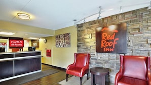 A Red Roof Inn reception area with a clock, a sign indicating free Wi-Fi, and two leather chairs.