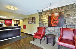 Zona de recepción de Red Roof Inn con un reloj, un cartel que indica Wi-Fi gratuito y dos sillones de cuero.