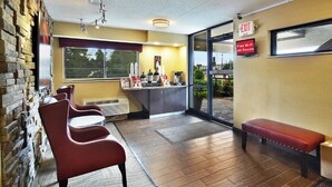 A hotel lobby with a seating area, a coffee station, and an exit sign.