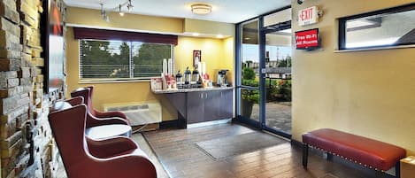 Un vestíbulo de hotel con zona de estar, estación de café y señal de salida.
