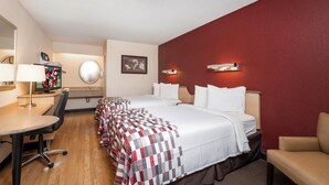 A hotel room with a bed, a desk, a chair, a TV, and a mirror.