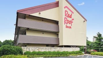 Un Red Roof Inn con una estructura de dos pisos, estacionamiento y zonas verdes circundantes.