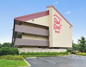 Un Red Roof Inn con una estructura de dos pisos, estacionamiento y zonas verdes circundantes.