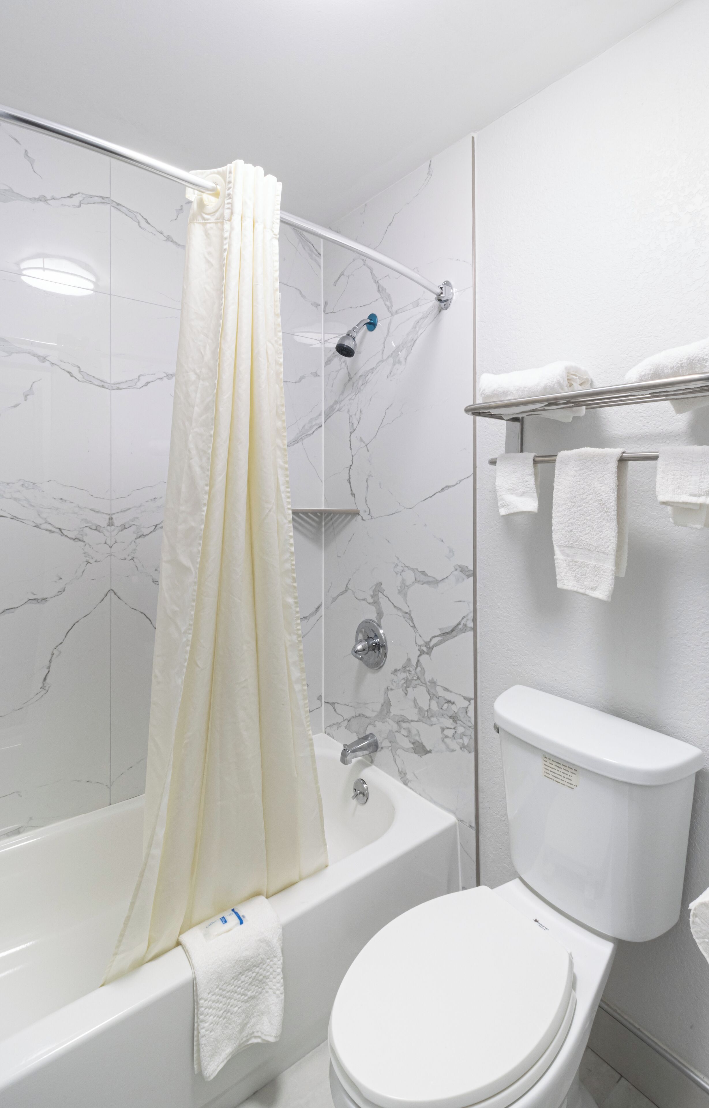 A bathroom with a bathtub, toilet, and shower curtain.
