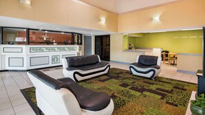 A spacious living area with a reception desk, two sofas, a dining table, and a kitchen area. - Rodeway Inn At Fort Lee (Hopewell)