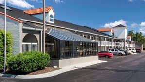A motel with a row of rooms featuring large windows and a covered walkway. - Rodeway Inn At Fort Lee (Hopewell)