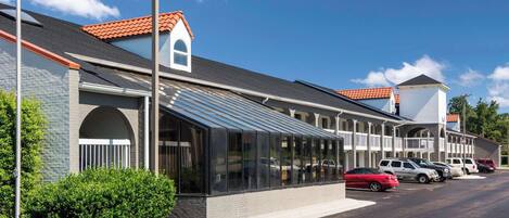 A motel with a row of rooms featuring large windows and a covered walkway.