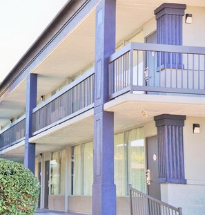 A multi-story building with a balcony on the second floor, large windows, and a door with a number plaque. - Hotel elev8 (Conroe)