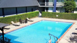 A rectangular pool with clear blue water, surrounded by lounge chairs and a small table. - Hotel elev8 (Conroe)