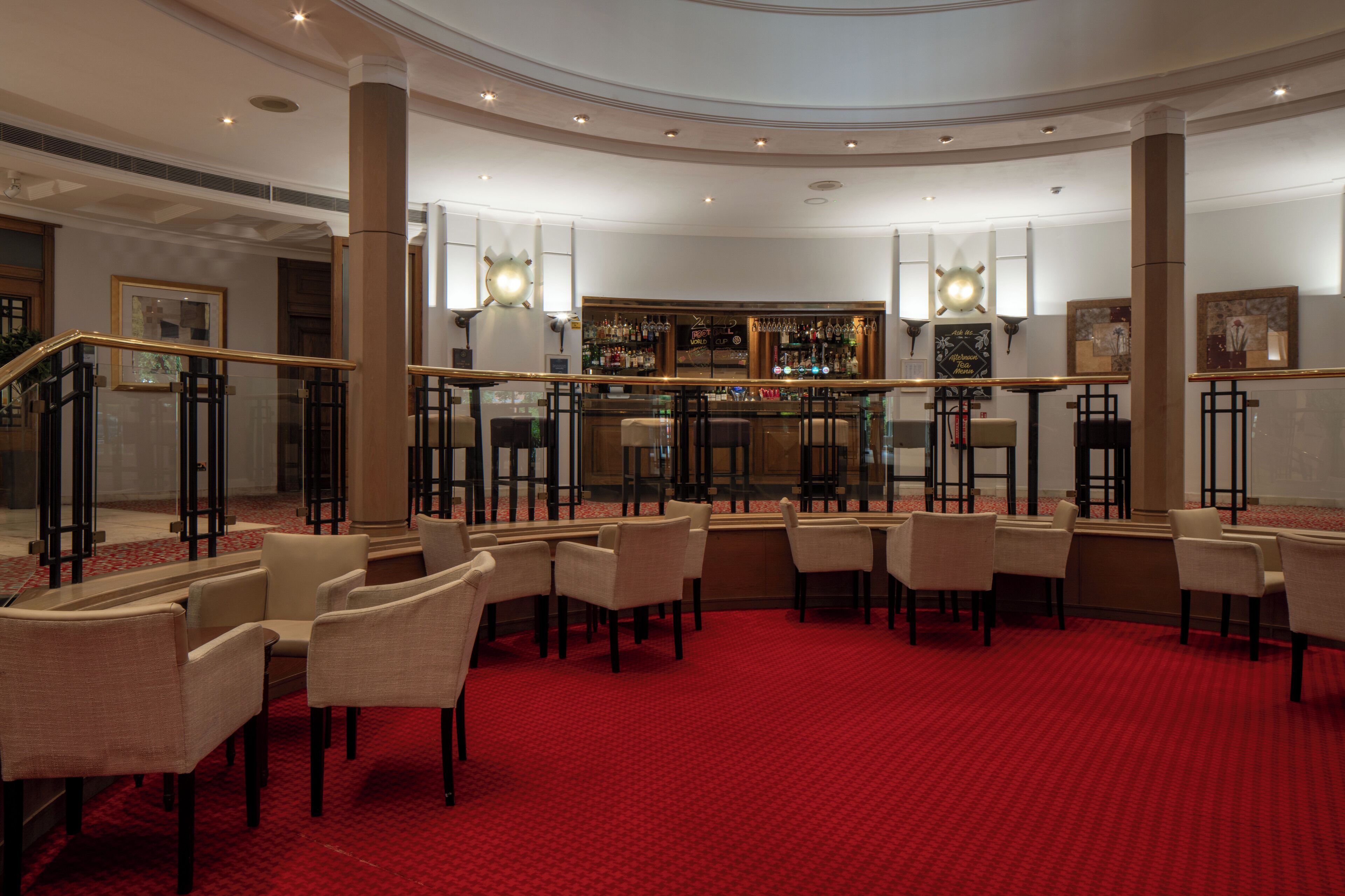 A hotel lobby with a bar area, seating arrangements, and a staircase.