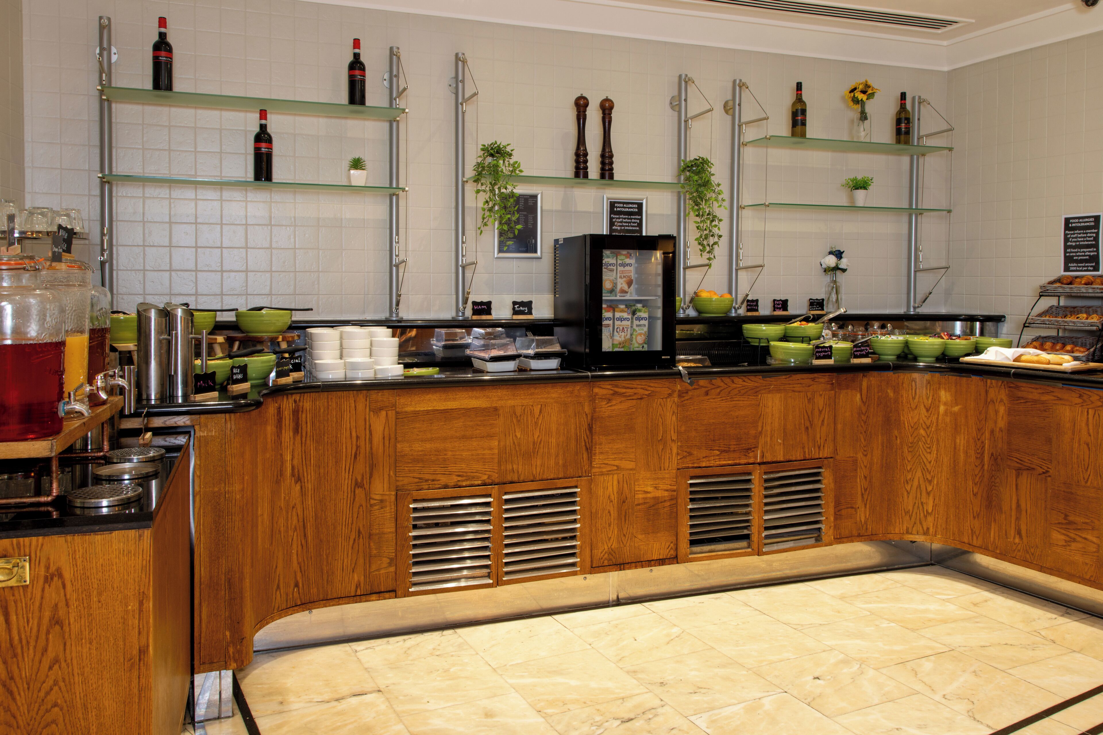 A kitchen area with a wooden counter, various food items, and shelves with bottles.