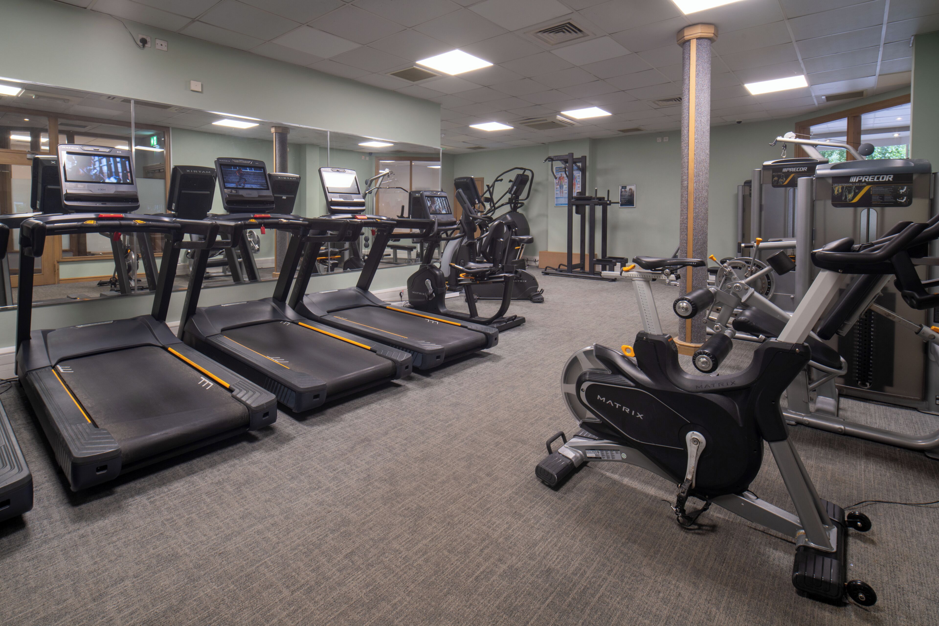 Ein Fitnessstudio mit Laufbändern, Crosstrainern und Gewichten.