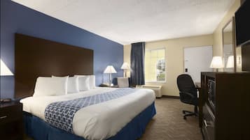 A hotel room with a large bed, two bedside tables, a desk with a chair, a TV, and a window with curtains.