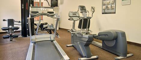 Ein Fitnessraum mit Cardiogeräten, Gewichten und einem Wasserspender.