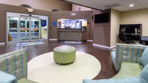 A lobby with a reception desk, seating area, and a television screen.