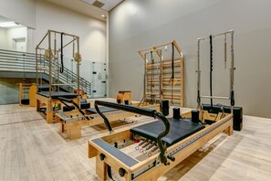 A Pilates studio with equipment, wooden floors, and a staircase in the background.
