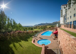 Una piscina cubierta, una piscina al aire libre, sombrillas