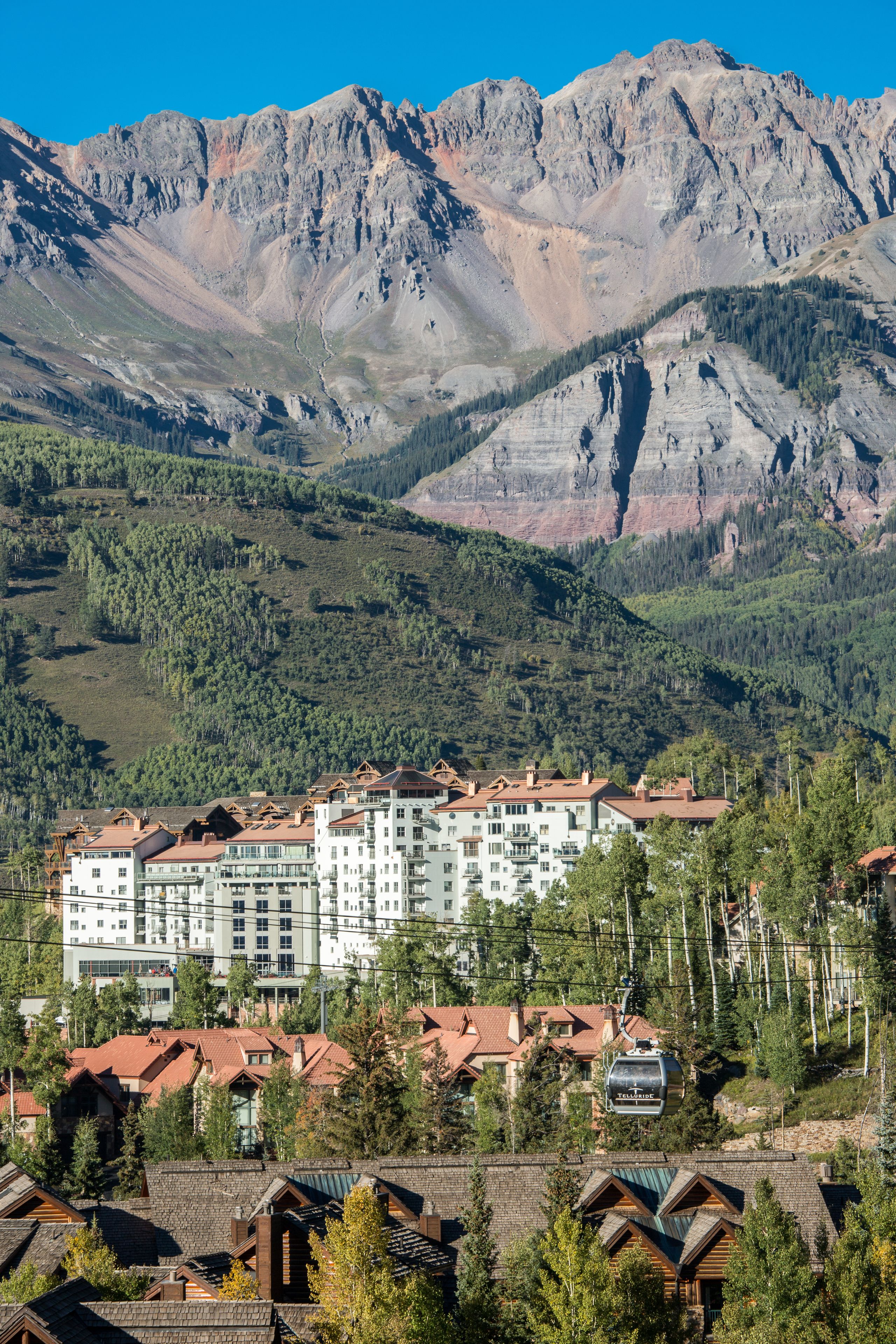 Un hotel de varios pisos, un telesilla y un paisaje montañoso de fondo.