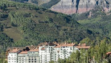 A hotel with multiple floors, a ski lift, and a mountainous backdrop.