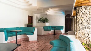 Un interior moderno con sofás color turquesa, una mesita redonda y una pared de piedra.