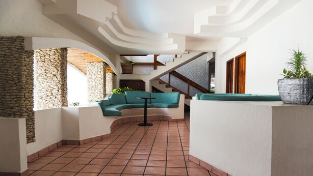Un interior espacioso con un sofá curvo, una escalera y una planta en maceta.