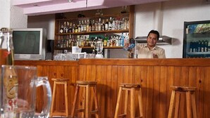 Un espace bar avec des tabourets en bois, un comptoir et des étagères remplies de bouteilles.