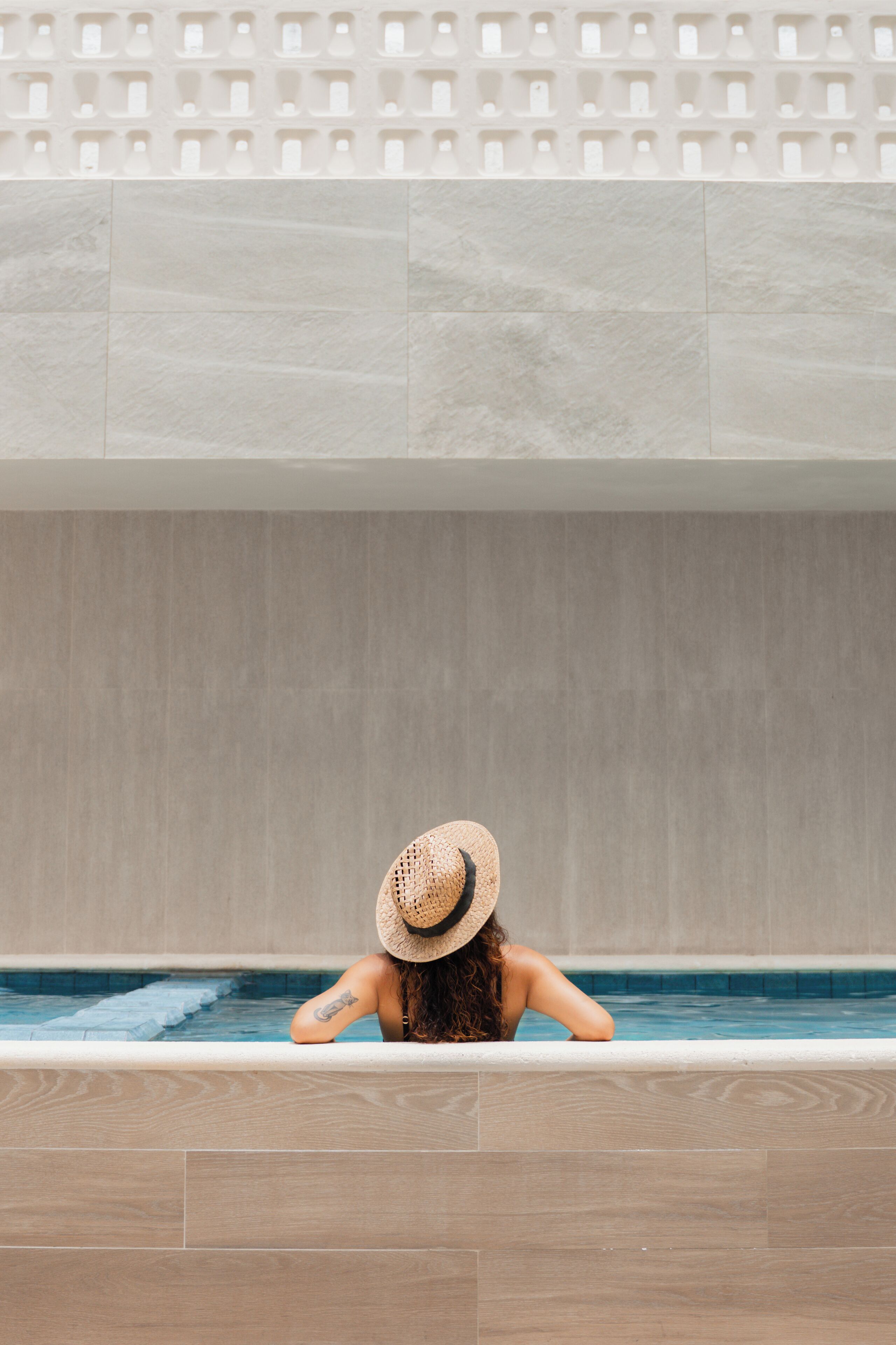 A person relaxing in a bathtub with a tiled wall above.