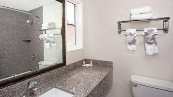 A bathroom with a granite countertop, a sink, a toilet, a mirror, and towel racks.