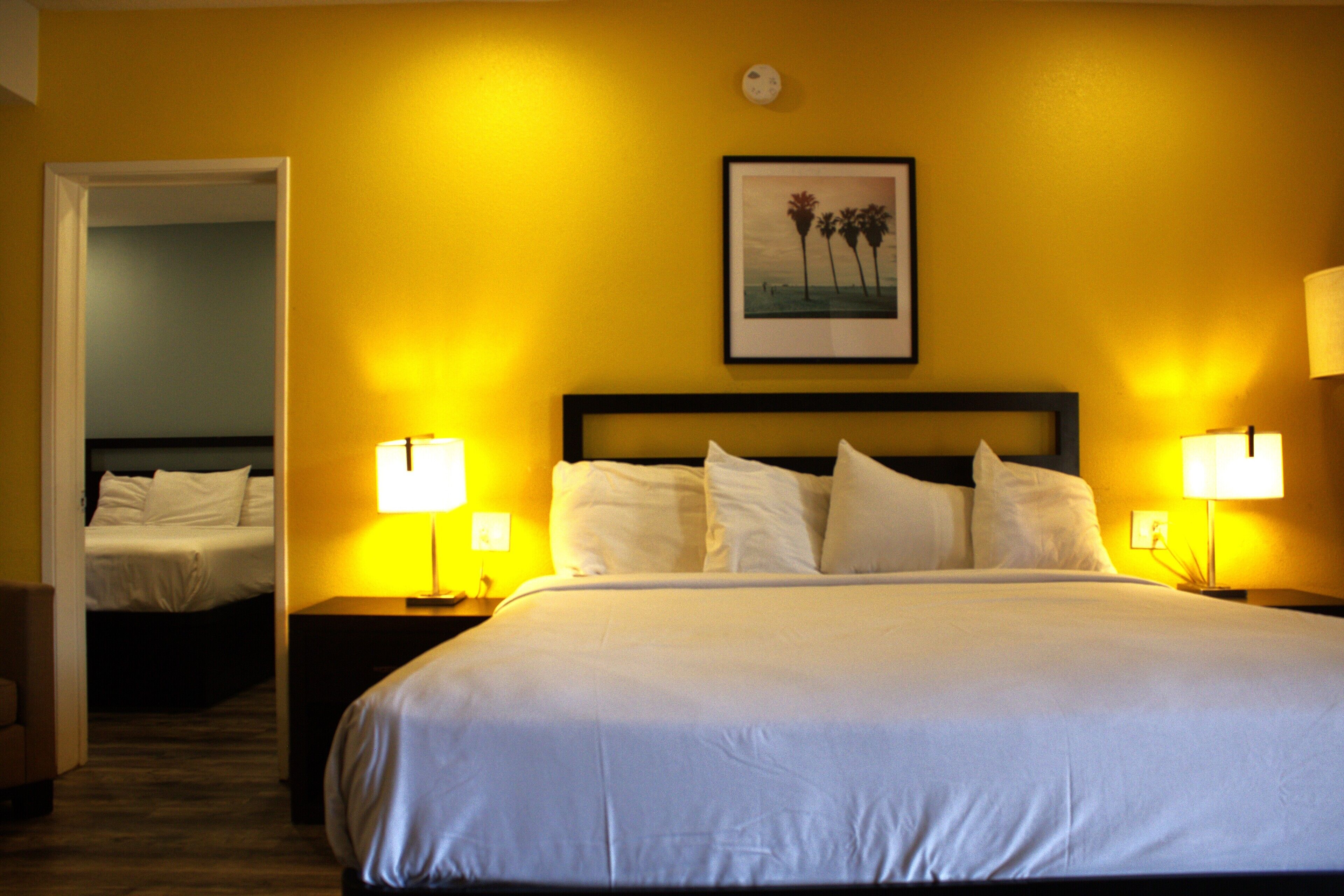 A hotel room with a large bed, two bedside lamps, and a framed picture on the wall.