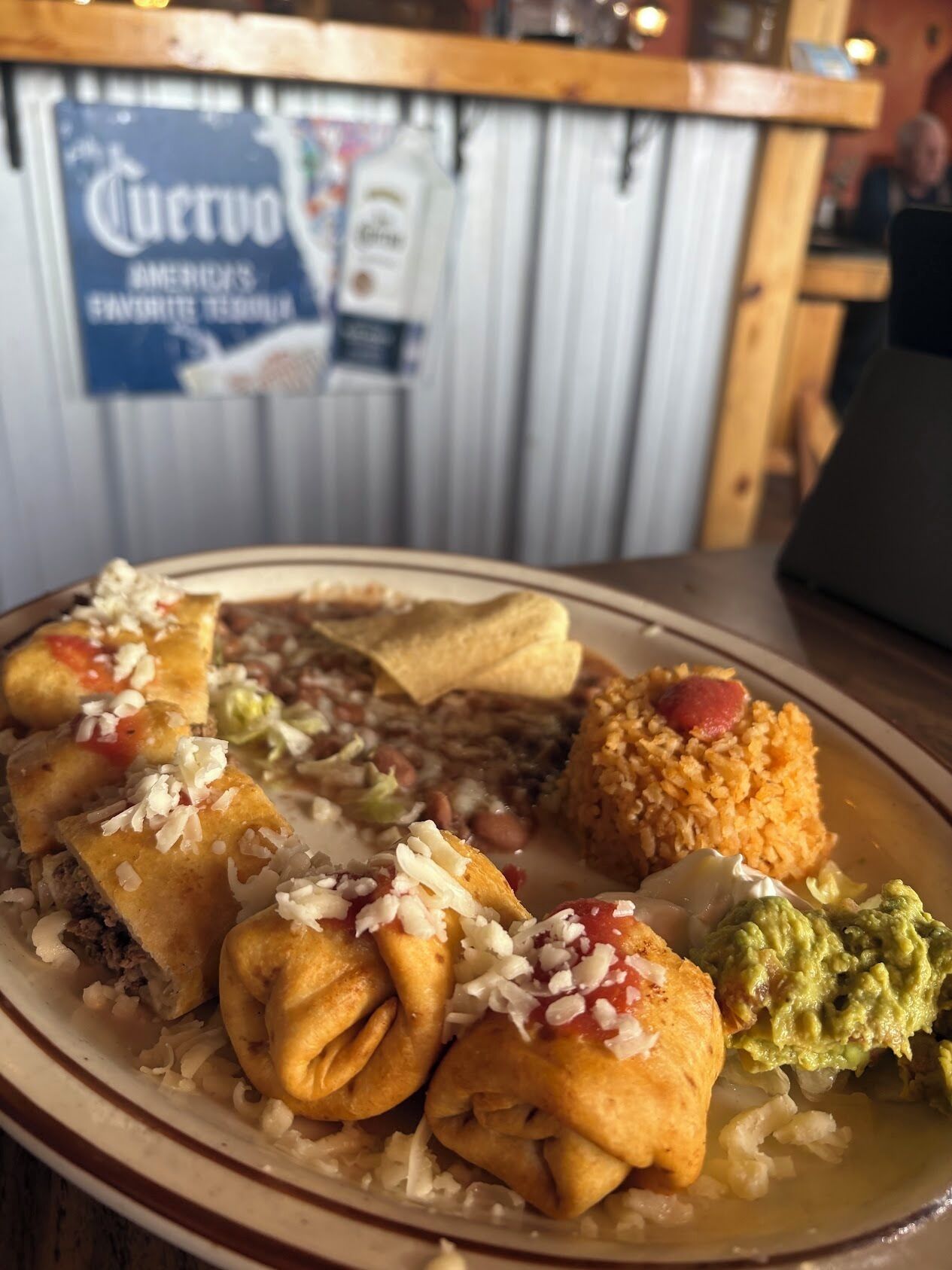 A plate of food with tacos, beans, rice, and guacamole.