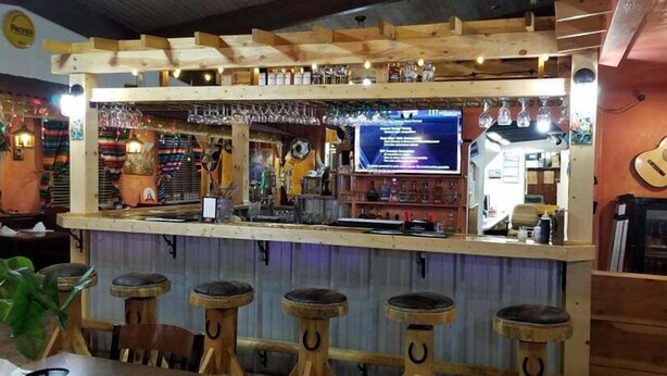 A bar area with stools, a counter, and a menu board.