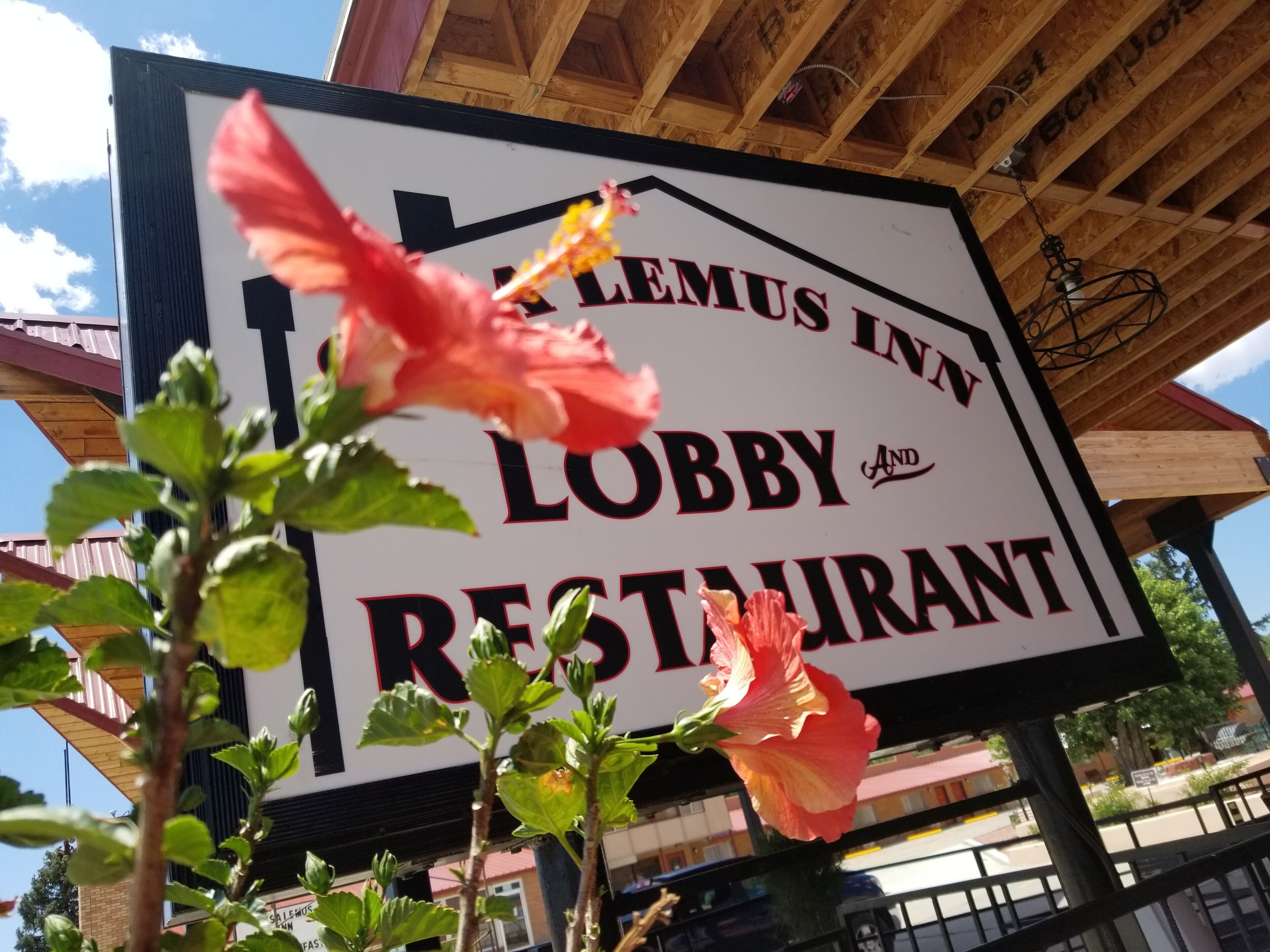Señal para el vestíbulo y restaurante Lemus Inn, con una estructura de madera y cielo despejado al fondo.