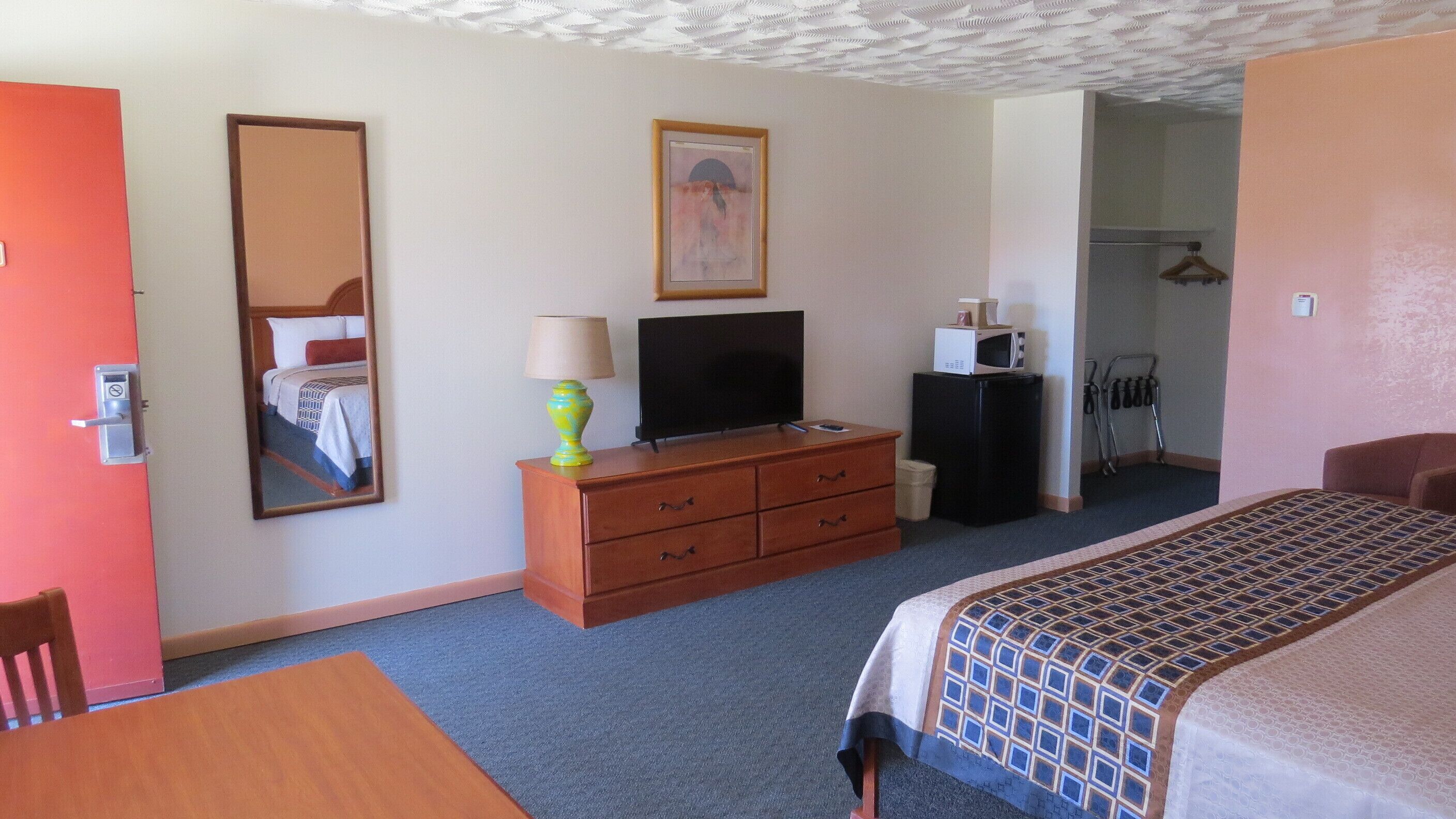 Une chambre d’hôtel équipée d’un lit, d’une commode, d’une télévision, d’un four à micro-ondes et d’un miroir.