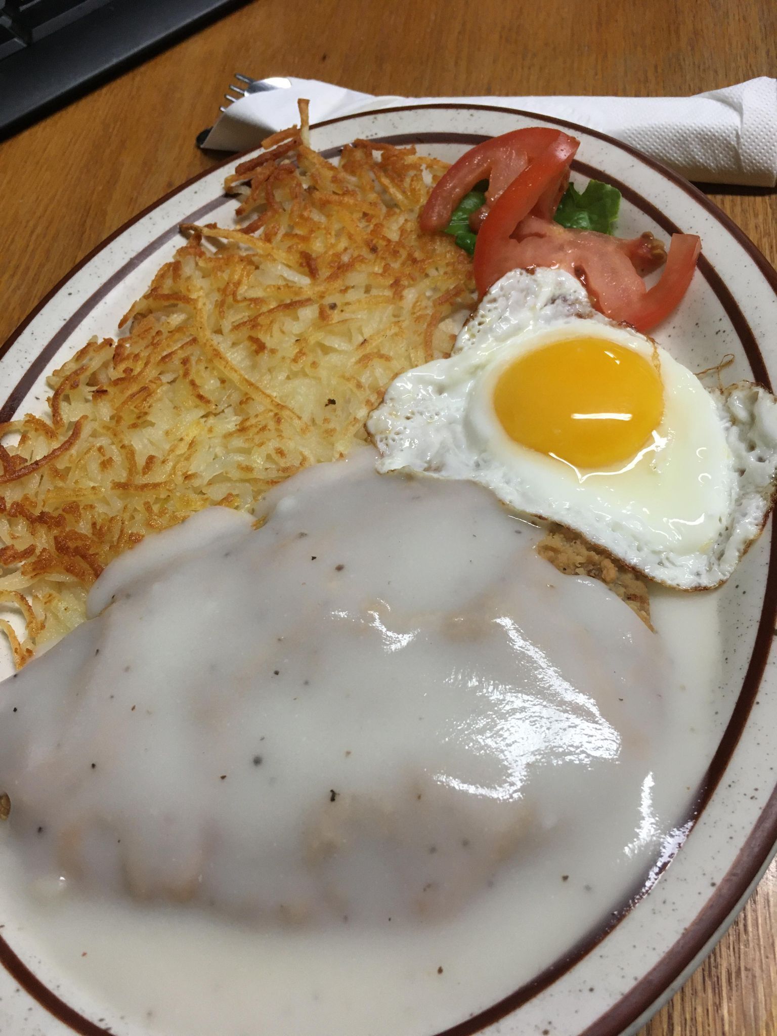 A plate with a hash brown, a fried egg, and a creamy sauce.