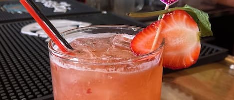 Een glas met een aardbeien garnering en een hartvormige decoratie op een bar.